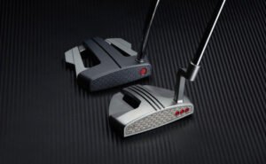 Two golf clubs resting on a dark textured surface, highlighting metallic club heads and shafts.
