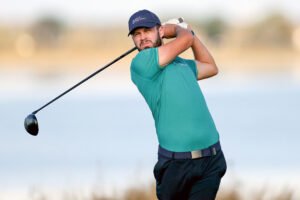 David Howard - Talk Golf Ireland Golfer in teal shirt mid-swing on a sunny golf course.
