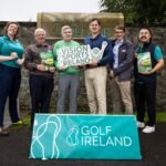 Group of six adults posing outdoors behind a turquoise Golf Ireland sign, holding golf brochures and a Vision Sports Ireland sign.