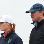 Two adults in outdoor jackets, the woman in a white cap on the left and the man in a blue plaid cap on the right (side profile).