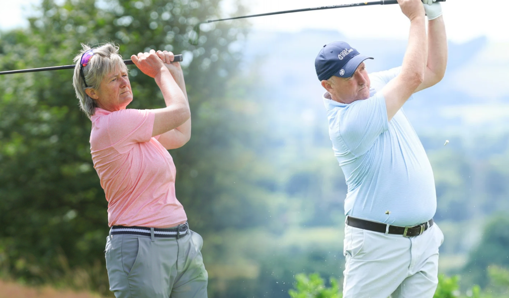 Two golfers, an older woman in a pink shirt and an older man in a light-blue shirt, swing their clubs on a sunny green golf course.