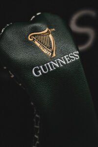 Close-up of dark green textured leather with the gold Guinness harp emblem and the word'GUINNESS'.