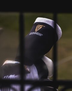 Close-up of a black leather boot with the Guinness harp logo and a white towel tucked inside the top edge.